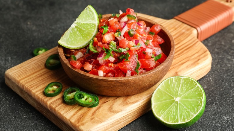 bowl of pico de gallo with lime on wooden board