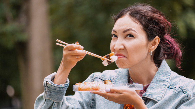 Woman holds sushi fish up to nose and notices off-putting smell