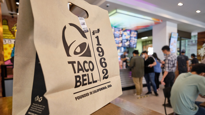 Taco Bell bag on table with customers ordering in background
