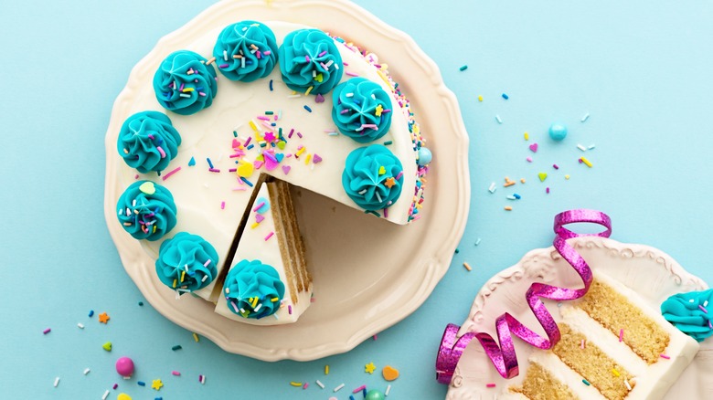 cake with white frosting and blue rosettes