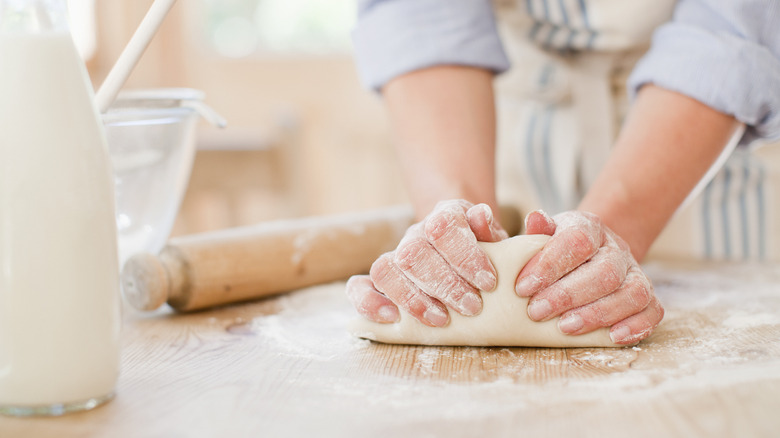 baker kneading dough with both hands