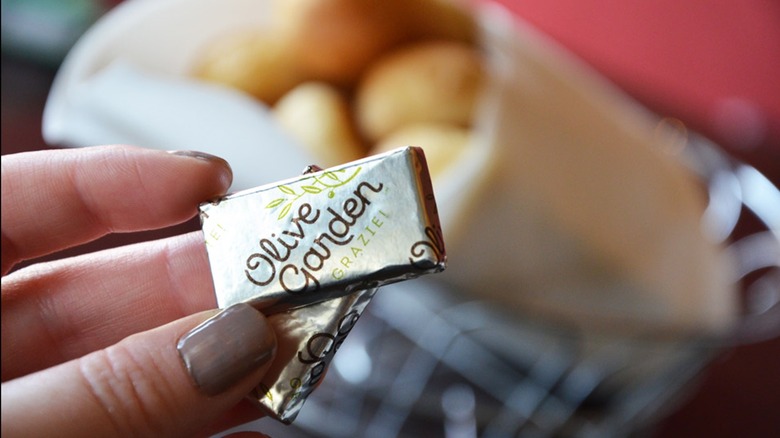 Manicured fingers hold two wrapped Olive Garden mints