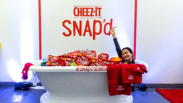 person in bathtub full of Cheez-It bags