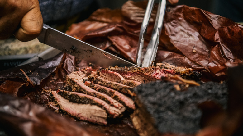 a person cutting brisket