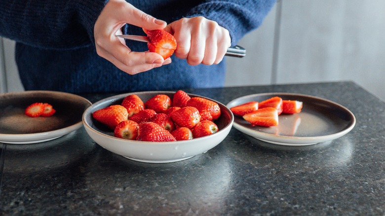 Person cutting strawberries in dish