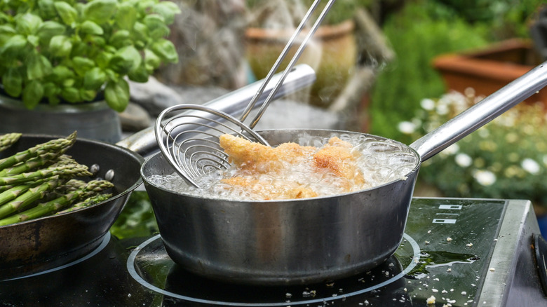Frying tempura in oil on cook top outside.
