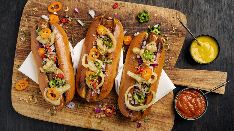 Three hot dogs topped with various condiments