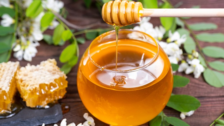 A cup of honey surrounded by flowers 