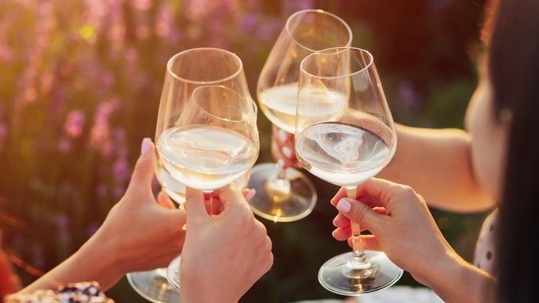 Three friends cheer glasses of white wine