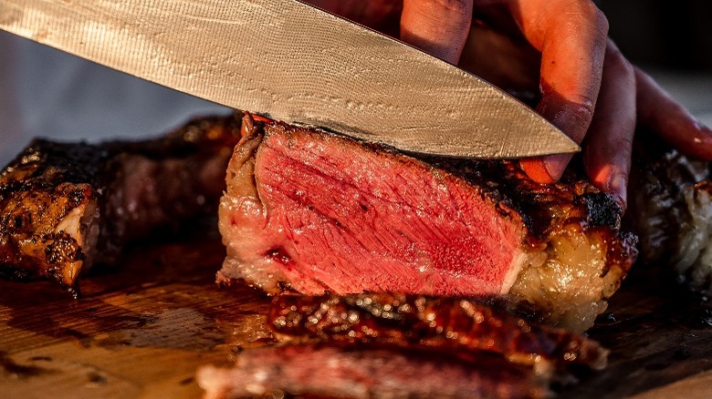 knife cutting into thick steak