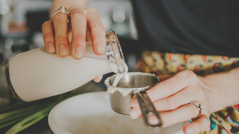 Woman pouring milk into measuring scoop
