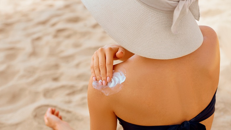 Woman applying sunscreen to shoulder