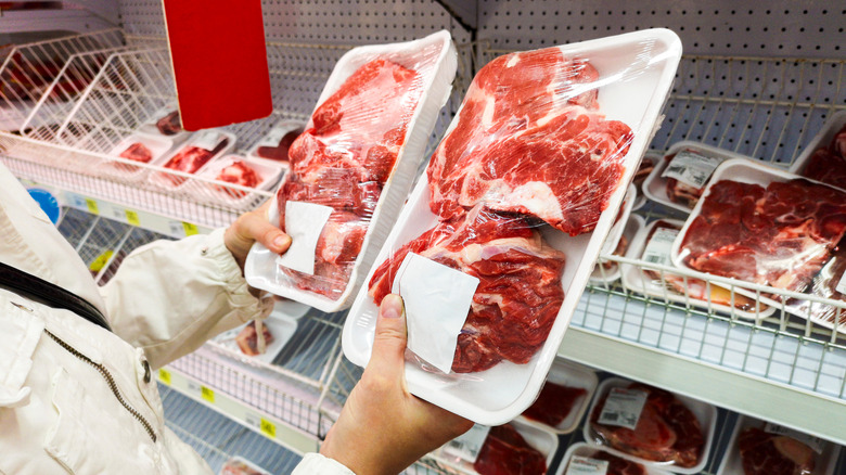 Person comparing packages of meat