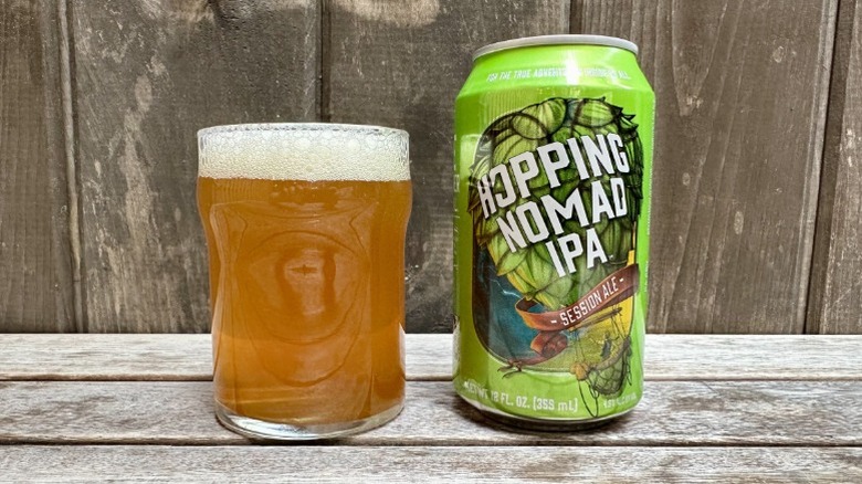 A can of Hopping Nomad IPA next to a glass of the beer