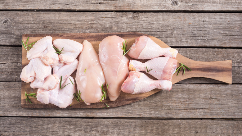 Raw chicken pieces cutting board