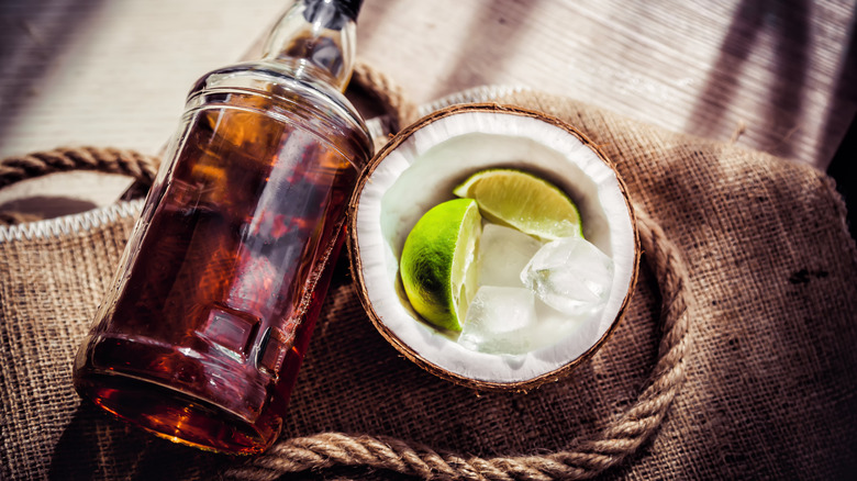 Bottle of rum with a lime, ice, and coconut