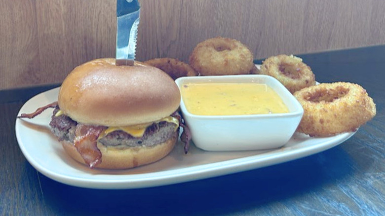 Red Robin's Cheesy Bacon Fondue Burger with onion rings on a white plate