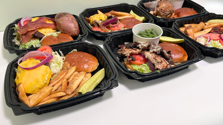 Six containers of Texas Roadhouse burgers and sandwiches against a white and green background