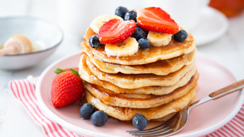stack of fluffy pancakes topped with fruit