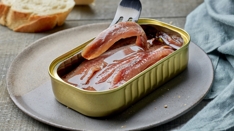 Anchovies in a can and on a fork