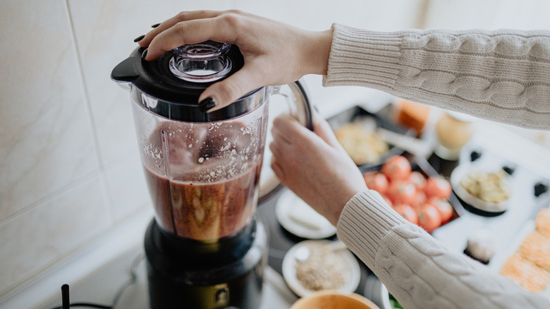 Hands turn on a blender