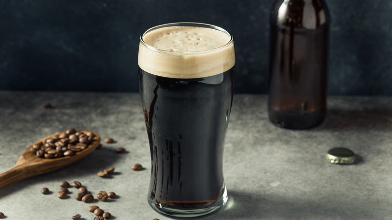 Glass of dark stout beer with coffee beans