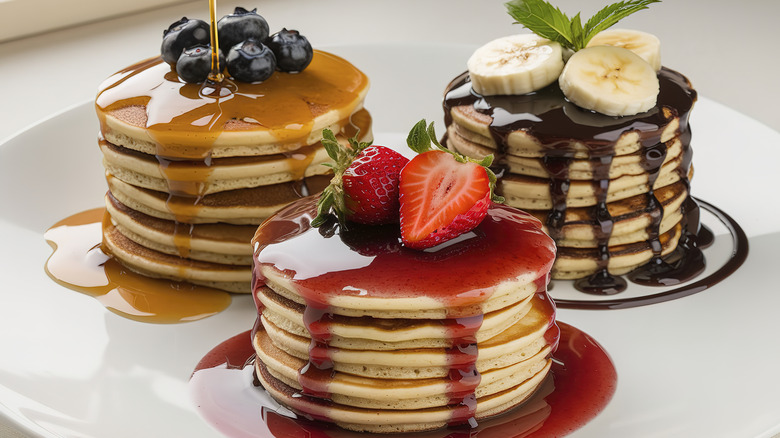 Three stacks of different varieties of pancakes with toppings
