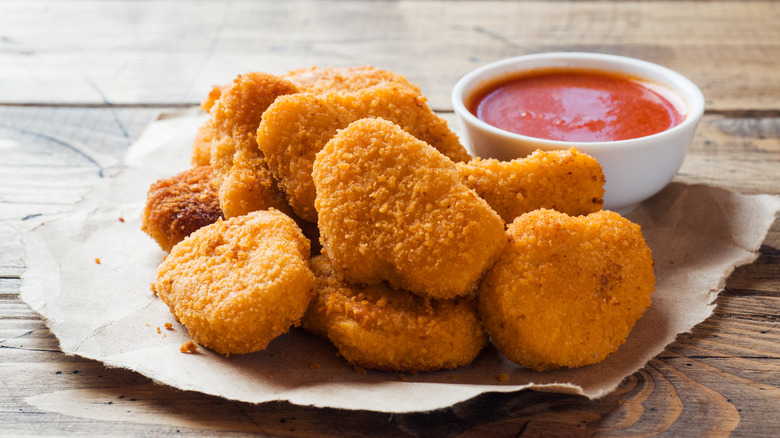 Chicken nuggets sitting next to a side of ketchup
