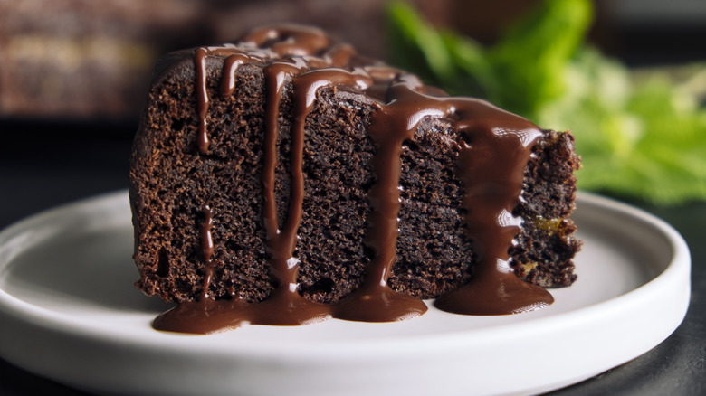 Rich chocolate cake with drizzle on white plate
