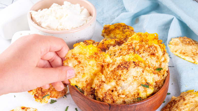 Hand grabbing cottage cheese chips from bowl