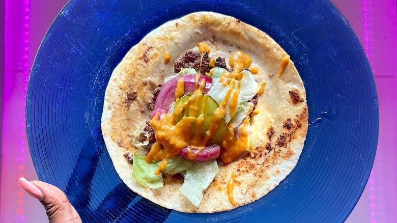 person holding a smash burger taco