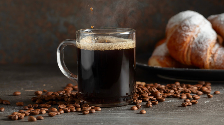 A wooden table with croissants and coffee being poured into a cup