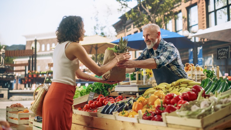 Woman buying produce at an open-air vegetable stall