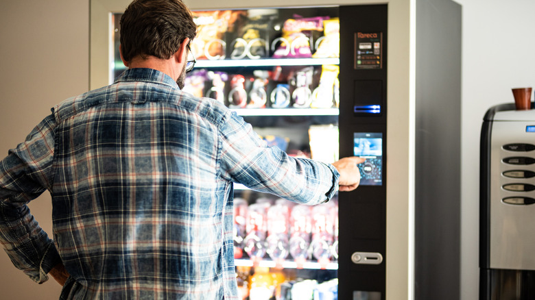 A man getting a snack from a vending machine