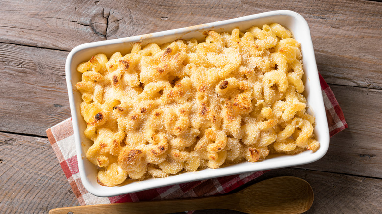 Casserole of macaroni and cheese baked with a golden brown top with a spoon in it