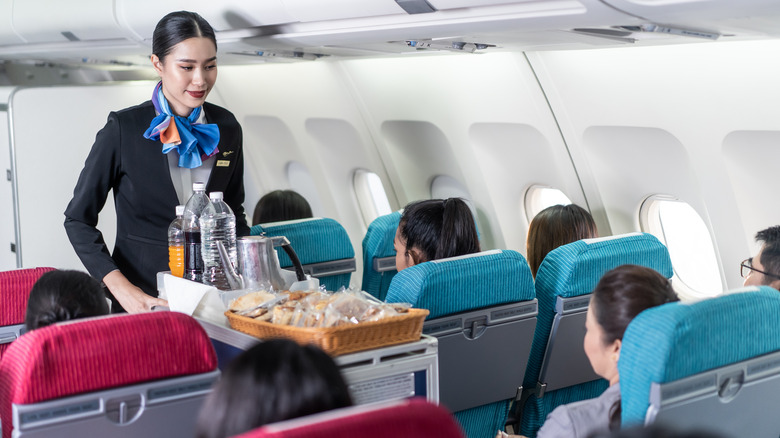 Flight attendant pushing cart with food 