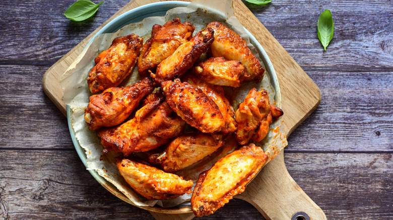 Plate of cooked chicken wings on wood board