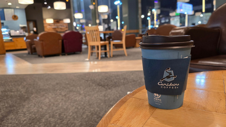 Caribou Coffee branded coffee cup sitting on a table in a public space