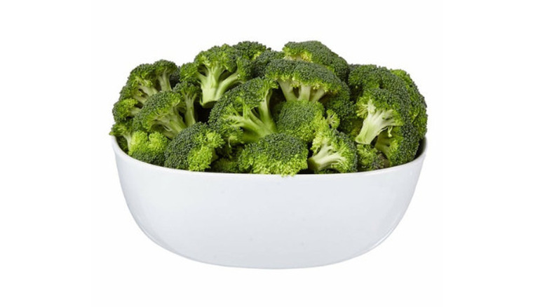 a bowl of broccoli florets against a white background