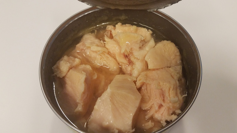 An opened can of canned chicken in broth