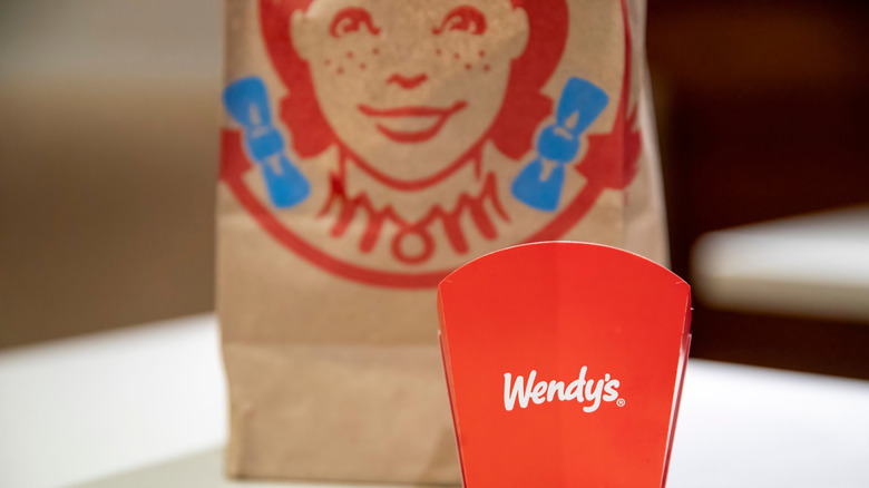 empty Wendy's french fries container next to a Wendy's bag