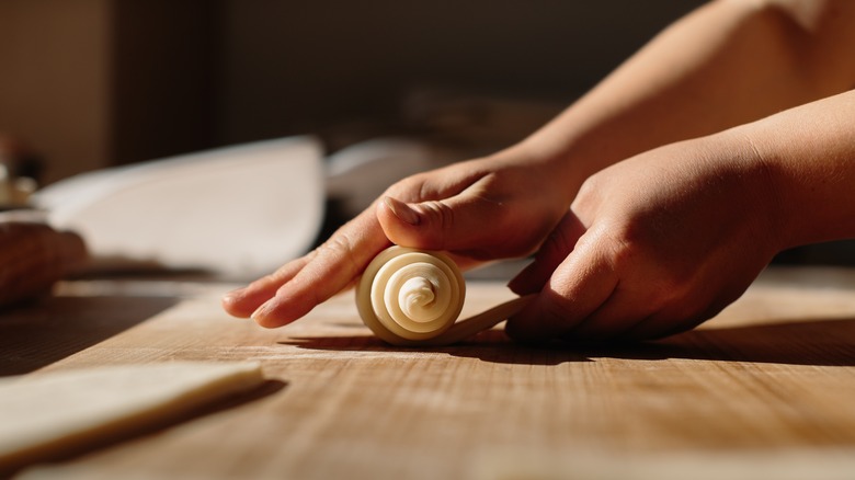 hands rolling a croissant