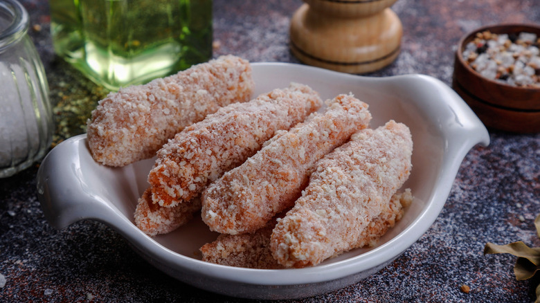 Breaded chicken strips in a white bowl placed on a black table