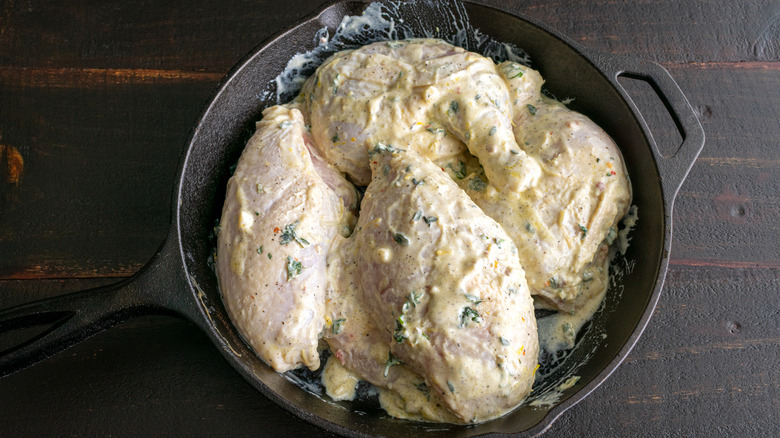 Chicken marinated with dairy in a skillet on a wooden table