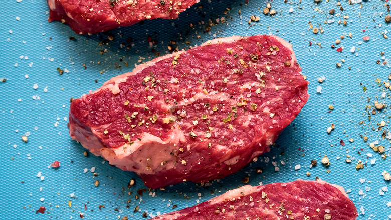 Raw steak seasoned with cracked pepper