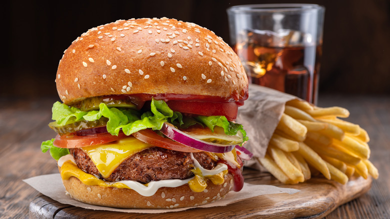 A cheeseburger with fries and a soda