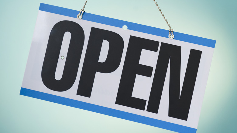 Blue and white 'Open' sign on light background