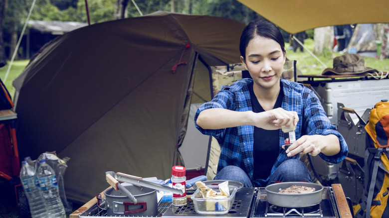 Camper seasoning food while cooking outdoors