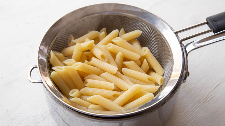 drained pasta in colander over saucepan