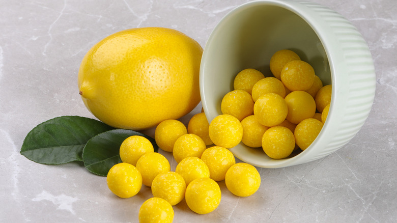 lemon drops candies spilling from a small ramekin next to a whole lemon